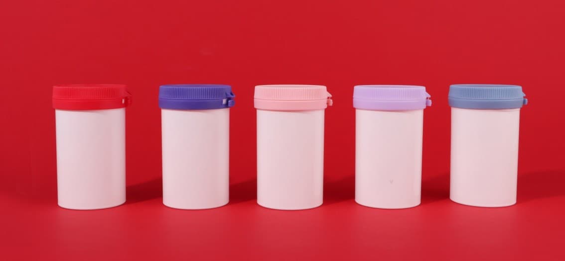 กระปุก PP สีขาวพร้อมฝาหลายสีบนฉากสีแดงสำหรับกลุ่มยา เวชภัณฑ์ และอาหารสุขภาพ